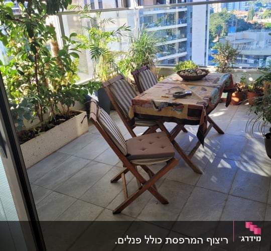 מרפסת עם רצפת אריחים, שולחן וכיסאות עץ